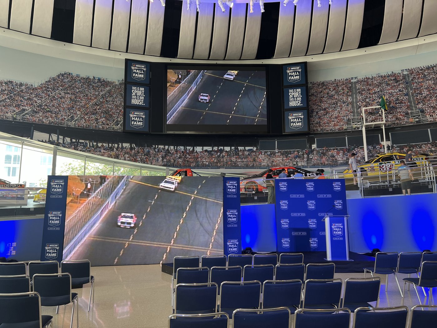 NASCAR Hall of Fame Class of 2024 stage setup with LED screens, branded towers, a podium and rows of chairs