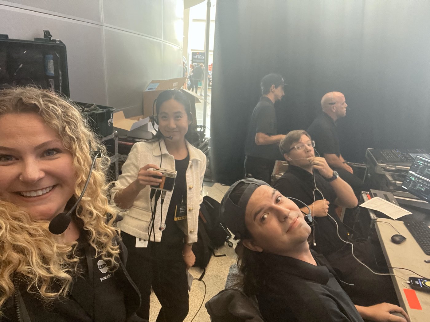 Alli Kaser taking a selfie with the production crew at the control desk, all wearing headsets